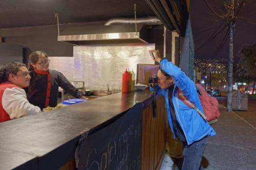 Rubén fotografía a Gato mientras retrata a los hermanos que atienden un negocio de comida rápida en la zona norte de Quito.